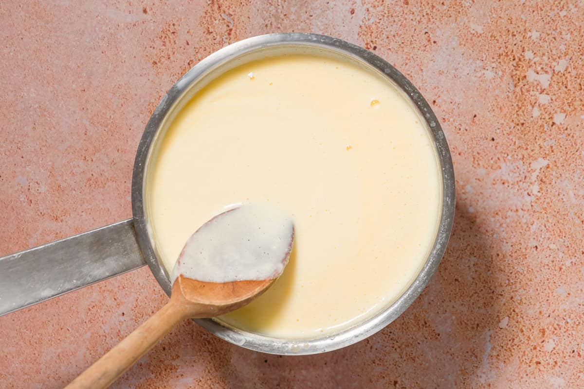 The mixture of the olive oil ice cream cooking in a saucepan with a wooden spoon.